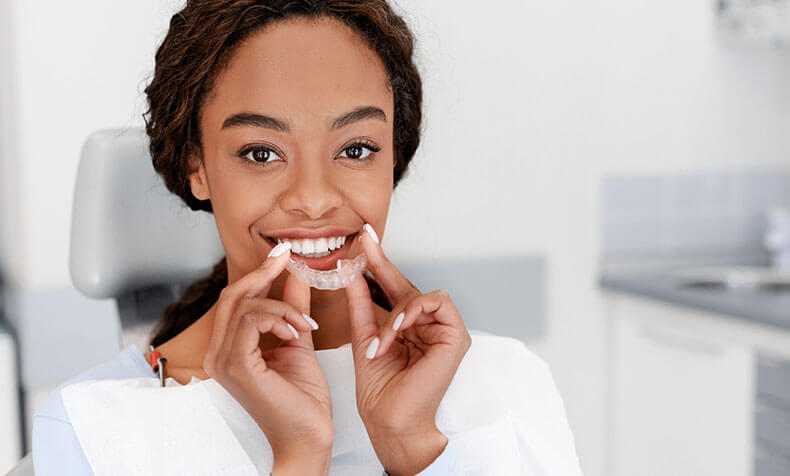 woman holding up a clear aligner